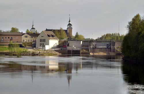 [Det nya kraftverket (som knappt syns vid vattenytan nedanför kyrkan) från Kuddnäs och den betydligt synligare dammen.