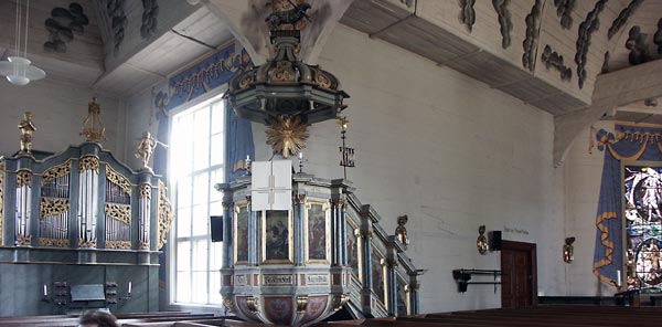 Telin-orgeln , predikstolen med lammet bärande sitt korsstandar, kollekthåvar, några ljusplåtar och Lennart Segerstråles glasmålning. Förstoring.