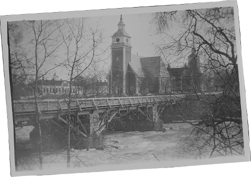 Kyrkan i islossningstid våren 1928. På förstoringen syns en planka eller bräda lutad mot kyrktornets högra sida. Foto: Axel Pensar.